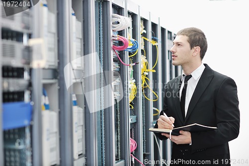 Image of businessman with laptop in network server room