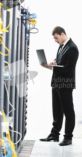 Image of businessman with laptop in network server room