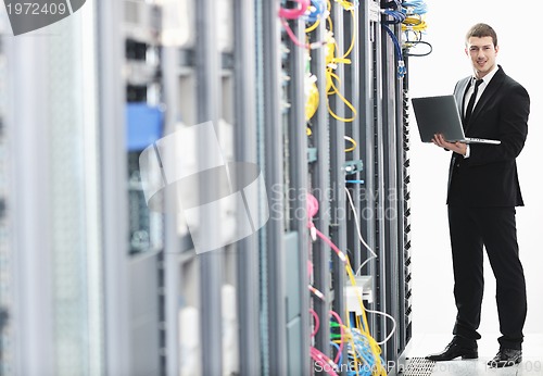 Image of businessman with laptop in network server room