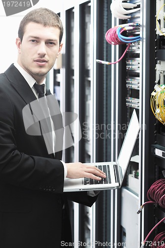 Image of businessman with laptop in network server room