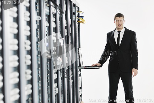 Image of businessman with laptop in network server room