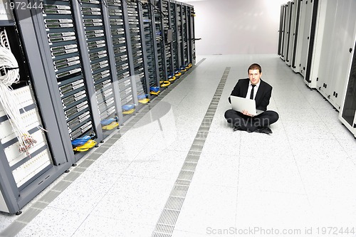 Image of businessman with laptop in network server room