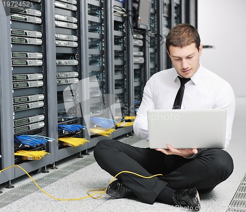 Image of businessman with laptop in network server room