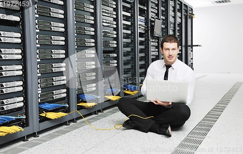 Image of businessman with laptop in network server room