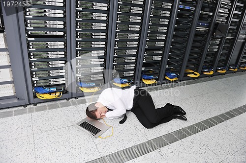 Image of businessman with laptop in network server room