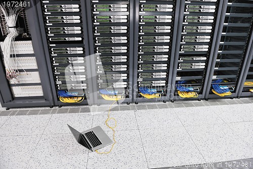 Image of businessman with laptop in network server room