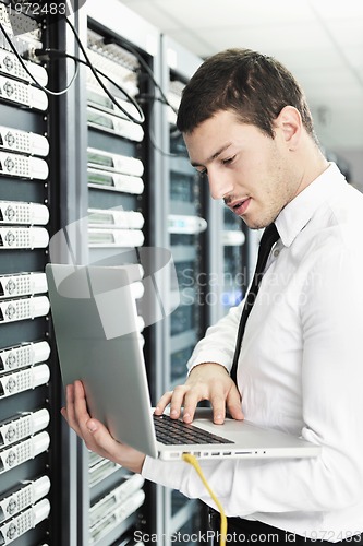 Image of businessman with laptop in network server room