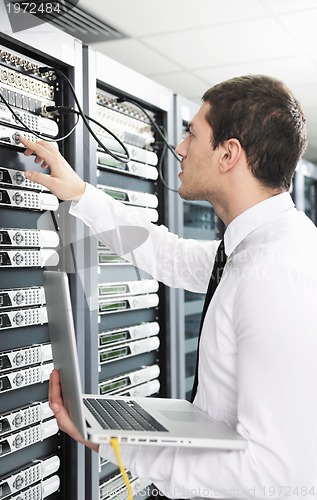 Image of businessman with laptop in network server room