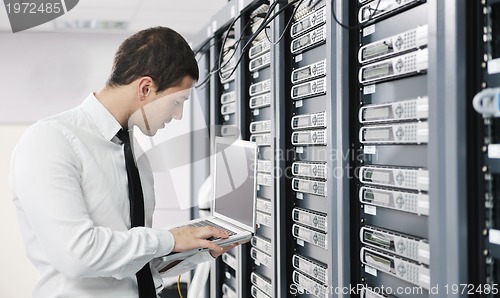 Image of businessman with laptop in network server room