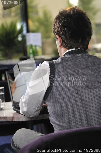 Image of Happy man sitting and working on laptop