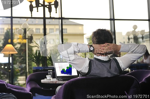 Image of Happy man sitting and working on laptop