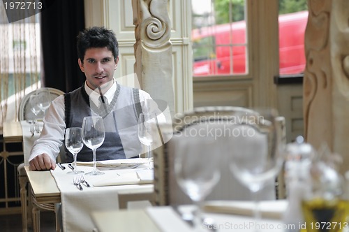Image of Young man sitting and waiting food at stylish restaurant