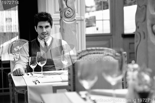Image of Young man sitting and waiting food at stylish restaurant
