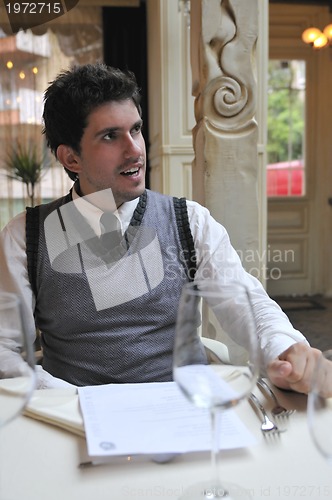 Image of Young man sitting and waiting food at stylish restaurant