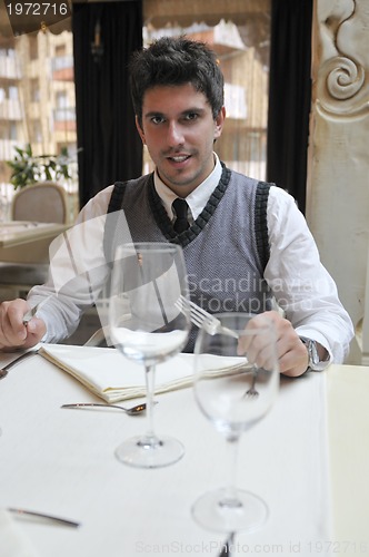 Image of Young man sitting and waiting food at stylish restaurant