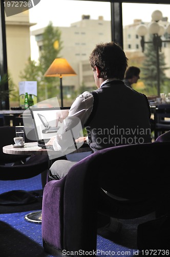 Image of Happy man sitting and working on laptop