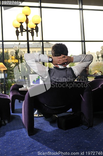 Image of Happy man sitting and working on laptop