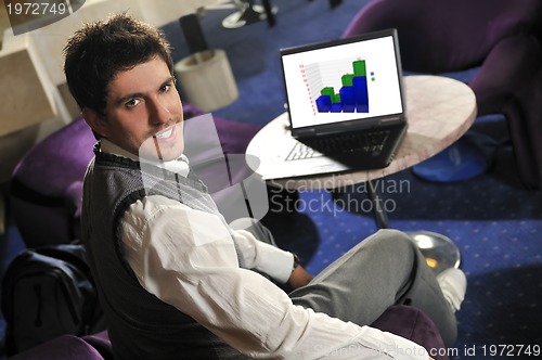 Image of Happy man sitting and working on laptop