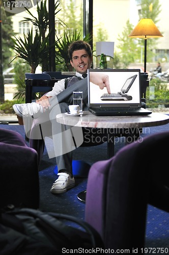 Image of Happy man sitting and working on laptop