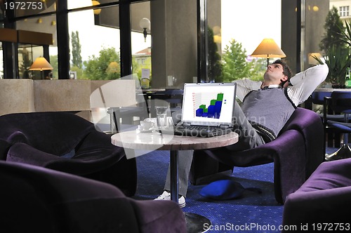 Image of Happy man sitting and working on laptop