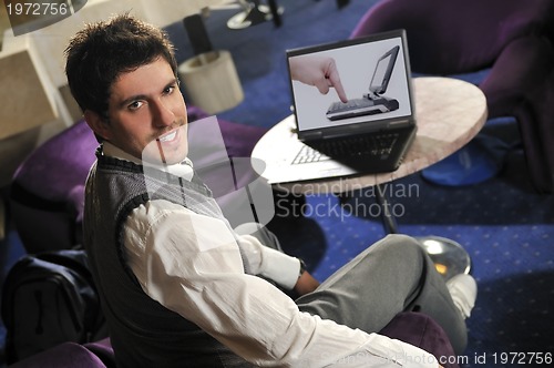 Image of Happy man sitting and working on laptop