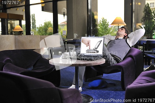 Image of Happy man sitting and working on laptop