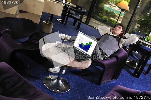 Image of Happy man sitting and working on laptop