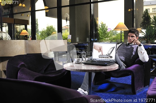 Image of Happy man sitting and working on laptop