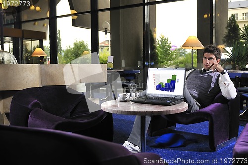 Image of Happy man sitting and working on laptop