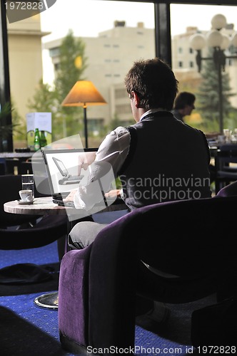 Image of Happy man sitting and working on laptop