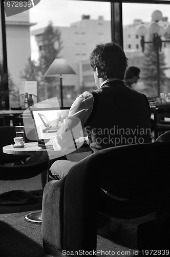 Image of Happy man sitting and working on laptop