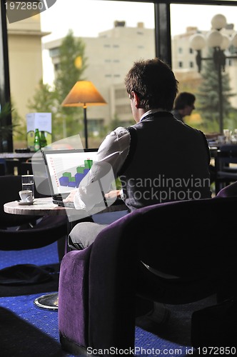 Image of Happy man sitting and working on laptop