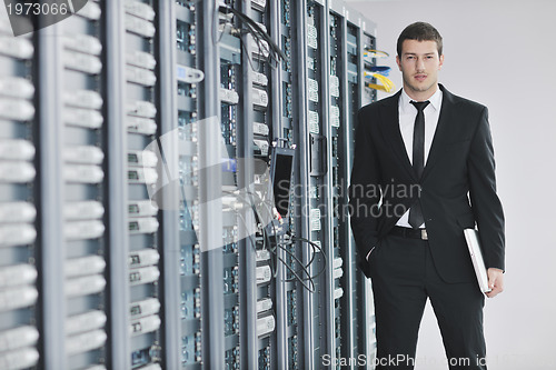 Image of businessman with laptop in network server room