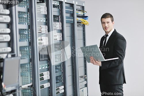 Image of businessman with laptop in network server room