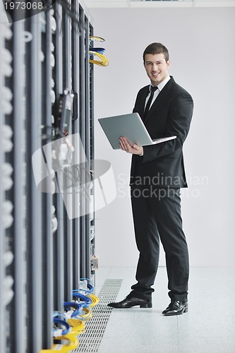 Image of businessman with laptop in network server room