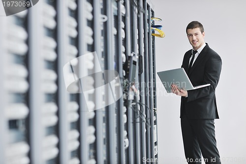 Image of businessman with laptop in network server room