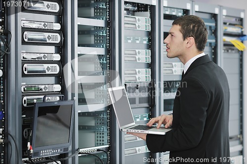 Image of businessman with laptop in network server room