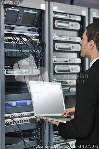 Image of businessman with laptop in network server room