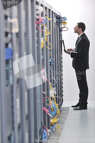 Image of businessman with laptop in network server room