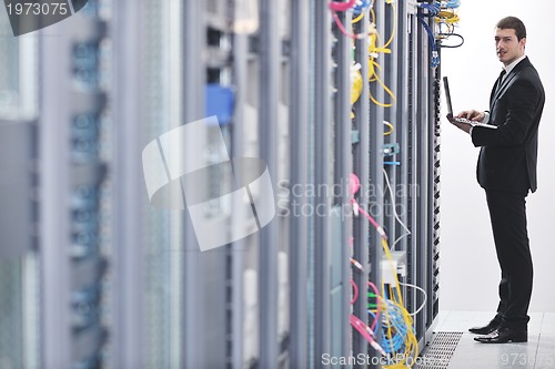 Image of businessman with laptop in network server room