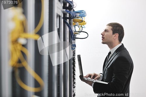 Image of businessman with laptop in network server room