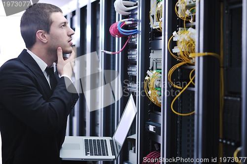 Image of businessman with laptop in network server room