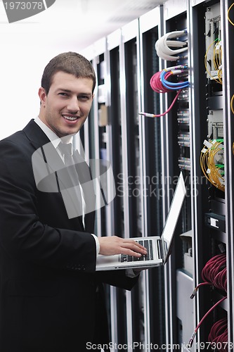 Image of businessman with laptop in network server room