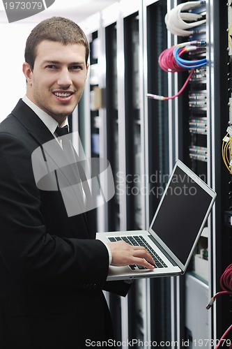 Image of businessman with laptop in network server room