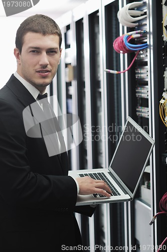 Image of businessman with laptop in network server room