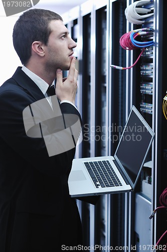 Image of businessman with laptop in network server room