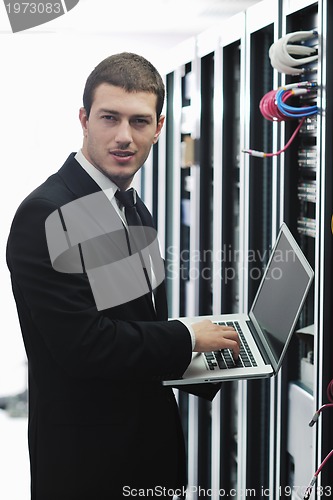 Image of businessman with laptop in network server room