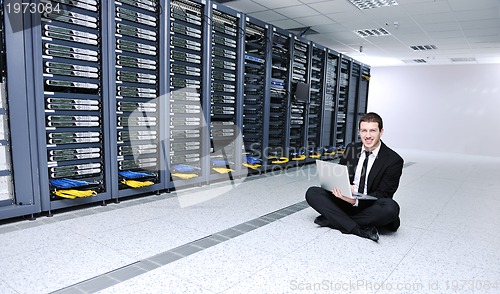 Image of businessman with laptop in network server room