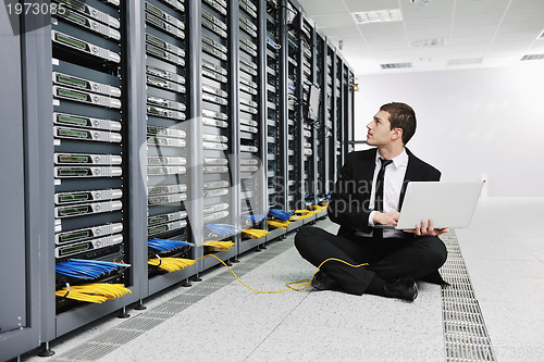 Image of businessman with laptop in network server room