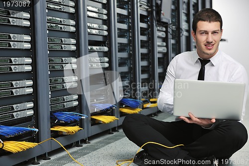 Image of businessman with laptop in network server room